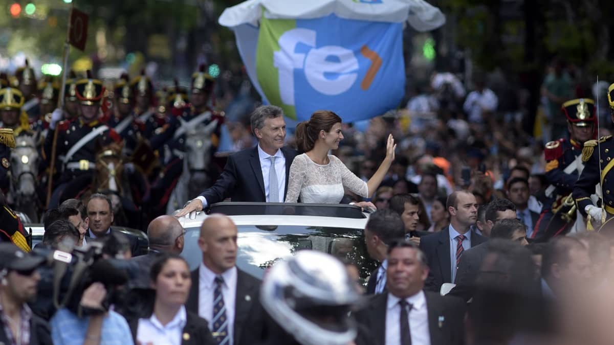 Presidentti Mauricio Macri ja puolisonsa Juliana Awada seisovat autossa, joka kulkee suuren ihmisjoukon keskellä.