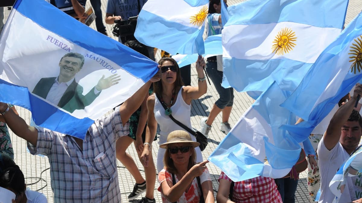 Ihmiset heiluttavat Argentiinan lippuja ja Mauricio Macrin kuvalla varustettua lippua.
