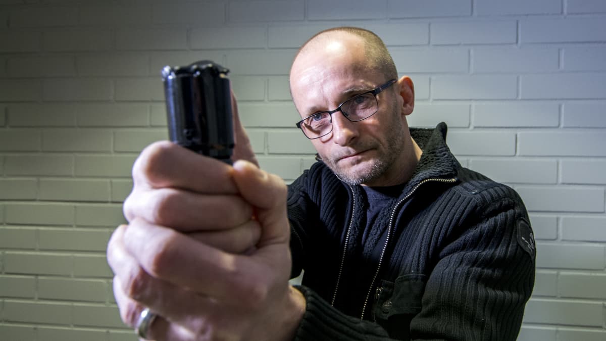 Mies osoittaa turvasumutteella kameraa kohti.