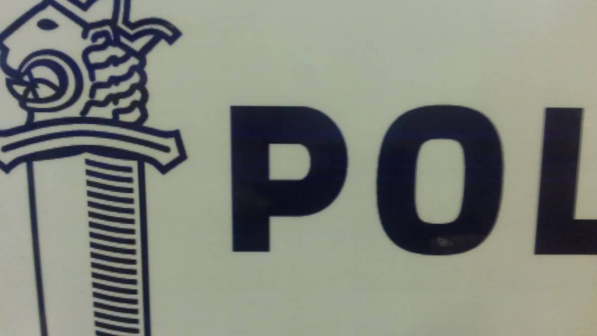 Sininen poliisin merkki ja osa poliisisanaa valkoisella pohjalla kyltissä.
