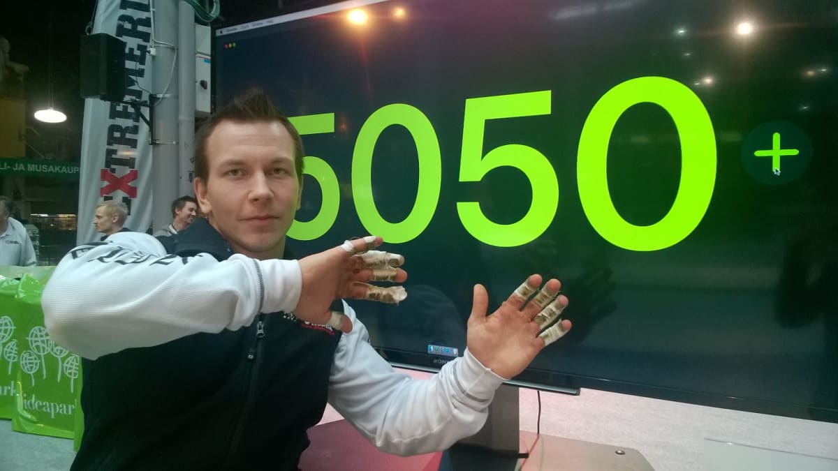 Joonas Mäkipelto poseeraa tulostaulun edessä.