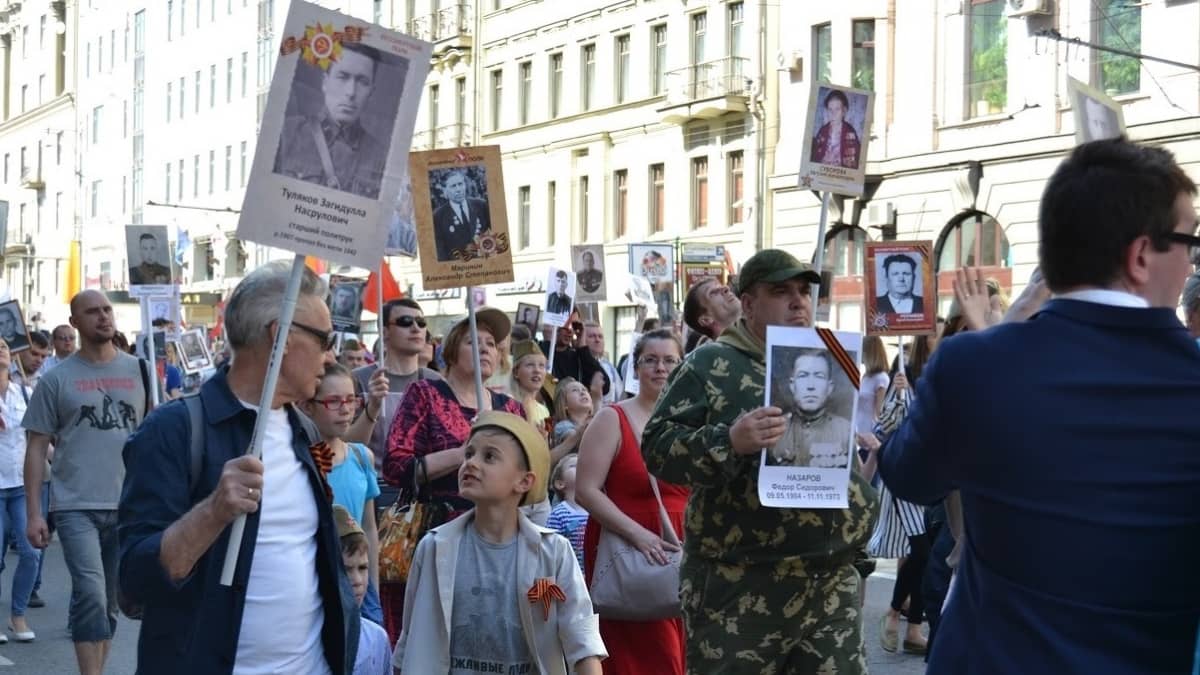 Arkiasuisia ihmisiä kantamassa julisteiksi tehtyjä valokuvia. 