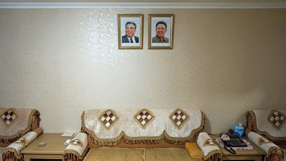 Olohuone seinällään johtajien kuvat. Maan entisten johtajien Kim Il-sungin ja Kim Jong-ilin kuvat koristavat Omin perheen olohuoneen seinää korkeammalla kuin mikään muu huoneessa. Kuvia on kohdeltava kodin arvokkaimpana omaisuutena. Poliisi voi tarkastaan niiden kunnon vaikka keskellä yötä.