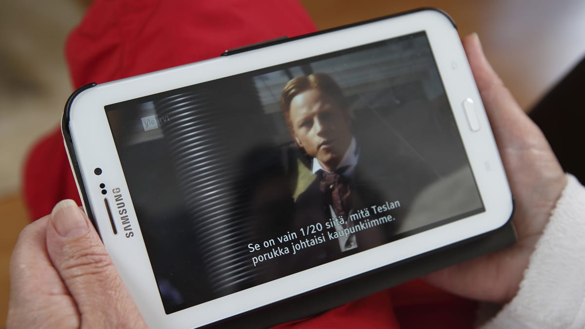 Nainen katselee televisiota älypuhelimella.
