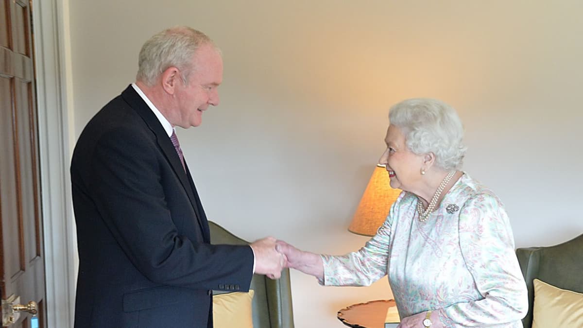 Hymyilevät Martin McGuinness ja kuningatar Elisabet kättelevät.