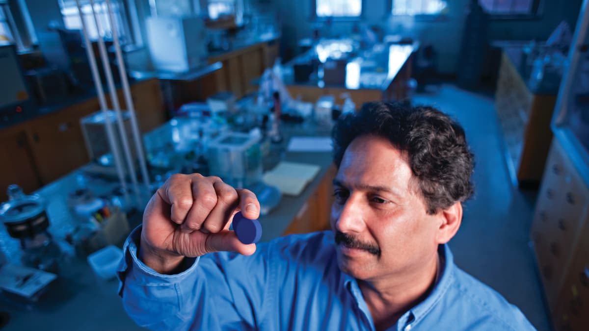 Kemisti Mas Subramanian pitää käsissään sinistä tablettia laboratoriossa.