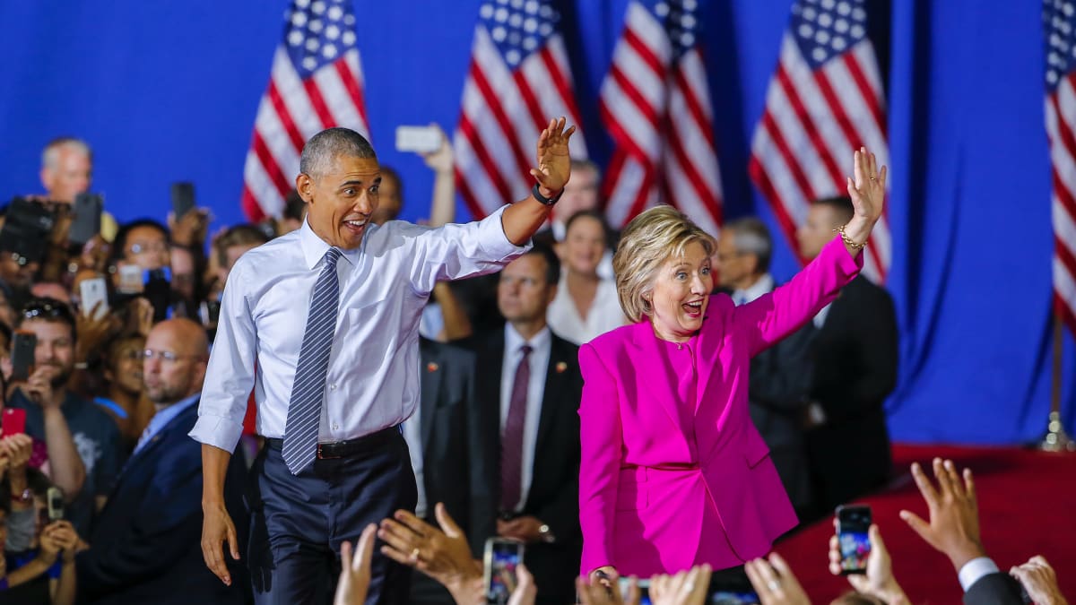 Demokraattien presidenttiehdokas Hillary Clinton pitää kampanjatilaisuuttaan yhdessä presidentti Barack Obaman kanssa. Charlotte, Pohjois-Carolina 5.7. 2016. Kuvassa parivaljakko vilkuttaa kansalle innokkaan ja vekkulin näköisinä.Taustalla liehuvat Yhdysvaltain liput.
