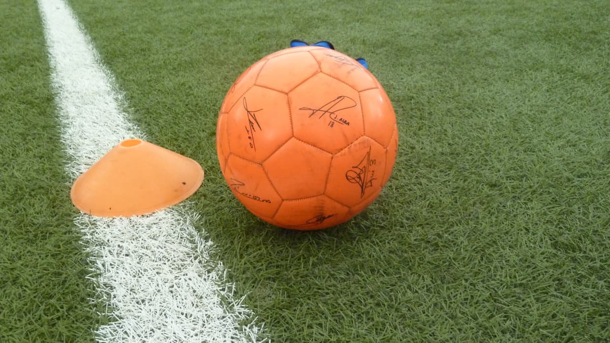 Nimikirjoituksilla varustettu jalkapallo tekonurmella.