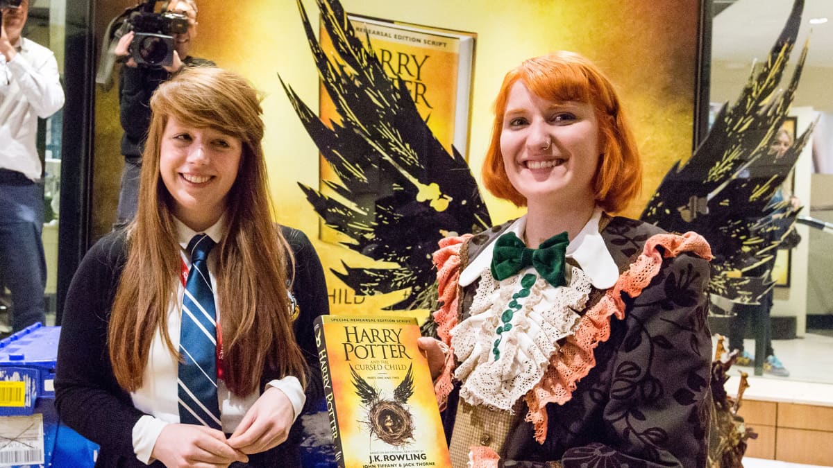 Kaksi naista joista toinen pitelee Harry Potter -kirjaa käsissään.