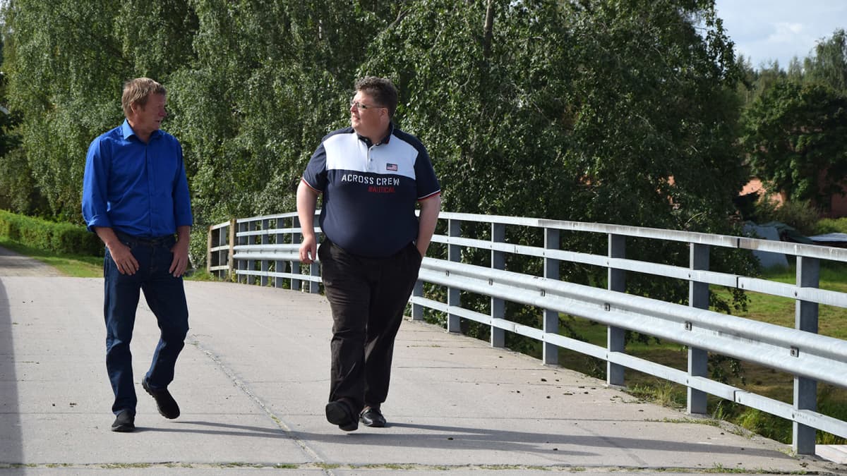 Kaksi miestä kävelee vanhaa Alvettulan siltaa elokuussa