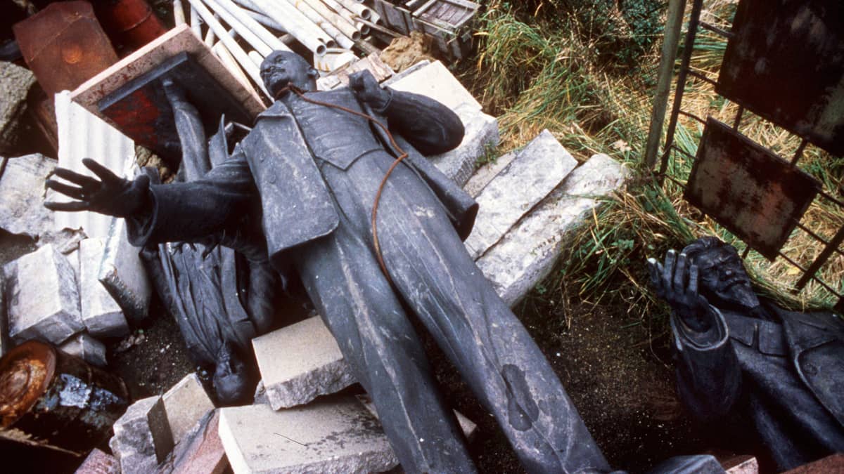 Tuhottu Leninin patsas makaa maassa roskien seassa.