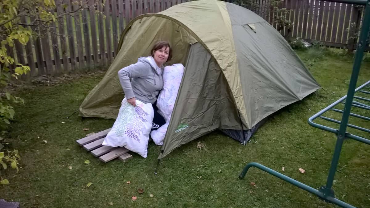 nainen vie tyynyjä telttaan