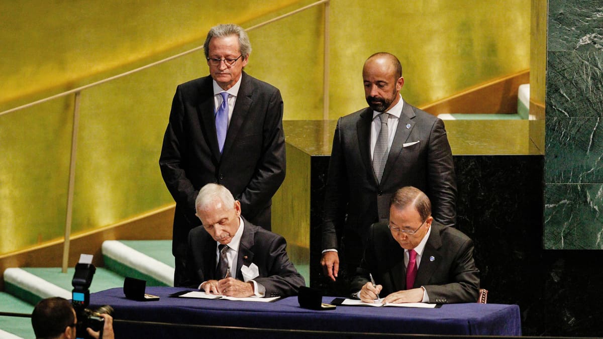 IOM:n puheenjohtaja William Lacy Swing ja YK:n pääsihteeri Ban Ki-moon allekirjoittavat sopimusta, jonka myötä  IOM liittyy osaksi YK-järjestelmää.