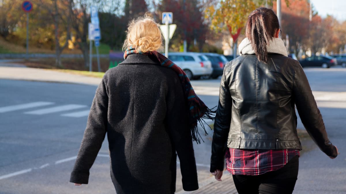 Kaksi tummiin pukeutunutta naista kävelee kadulla. 
