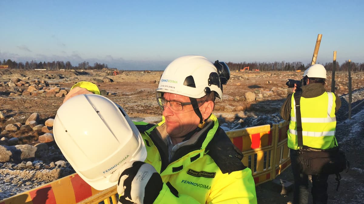 Rakentamisjohtaja Jouni Sipiläinen esitteli Hanhikivi 1 -ydinreaktorin sijaintipaikkaa 2016 auringonpaisteessa ja kypärä päässä.
