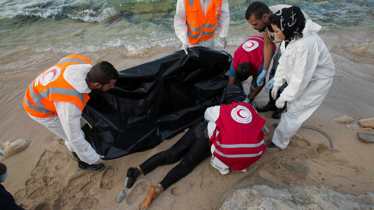 Libyan Punaisen Ristin edustajat peittävät Välimereen hukkuneen siirtolaisen ruumiin Libyan rannikolla. 