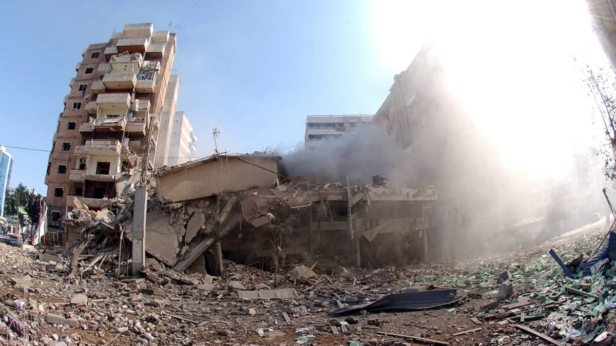 Pommituksen tuhoja. Kuvassa näkyy tuhoutunut rakennus ja räjähdyksen maahan heittämää rojua. Oikeassa laidassa leviää 