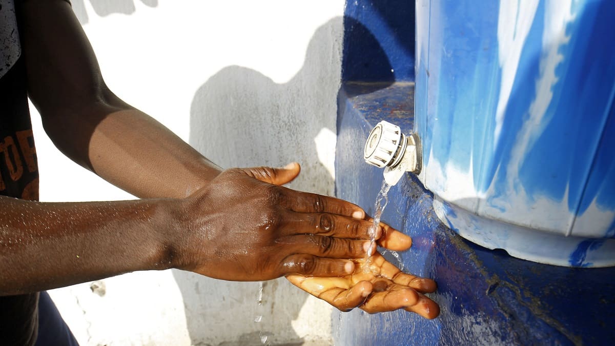 Käsien pesus sinisestä muovitankista tulee vettä. 