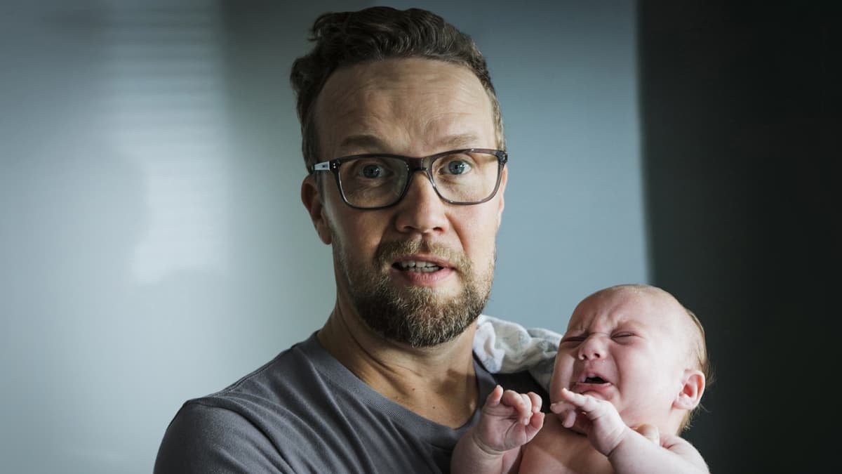 Mies pitää lasta sylissään.