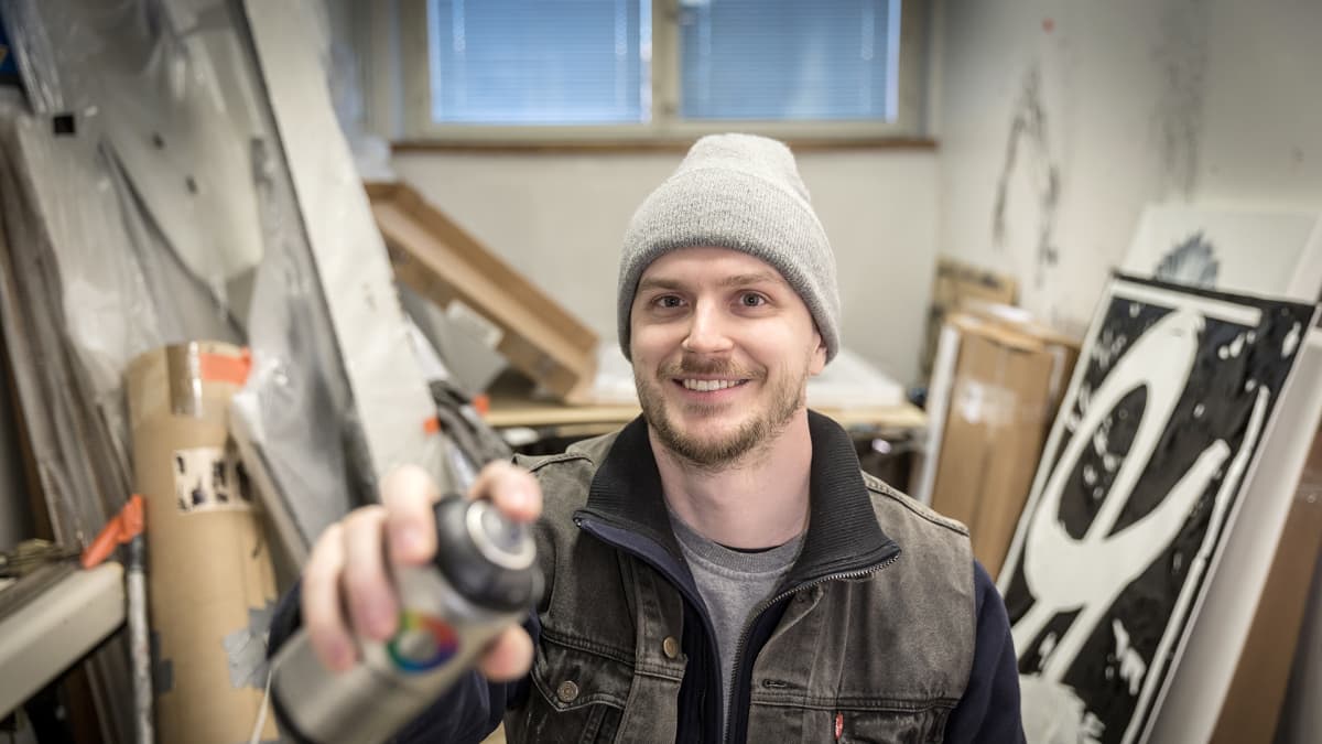 mies ateljeessa spraypullon kanssa