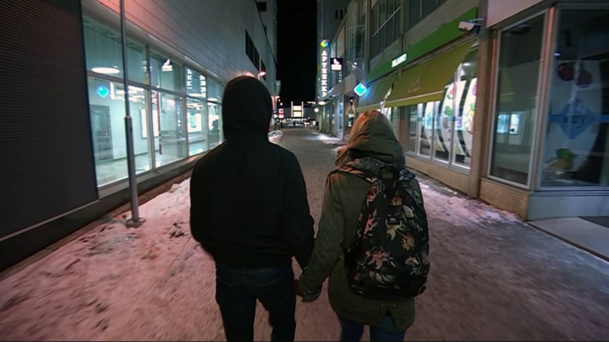 Kaksi nuorta kävelee kadulla talvi-iltana.