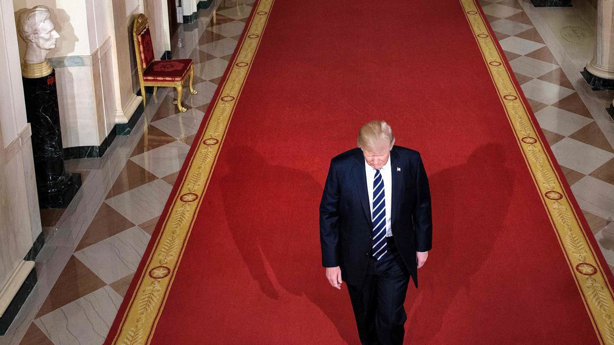 Donald Trump kävelee valkoisen talon käytävällä.