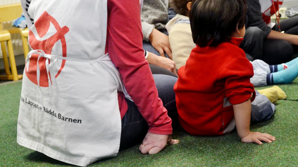 Pelastakaa Lapset ry:n vapaaehtoistyöntekijä istuu lapsen kanssa lattialla.