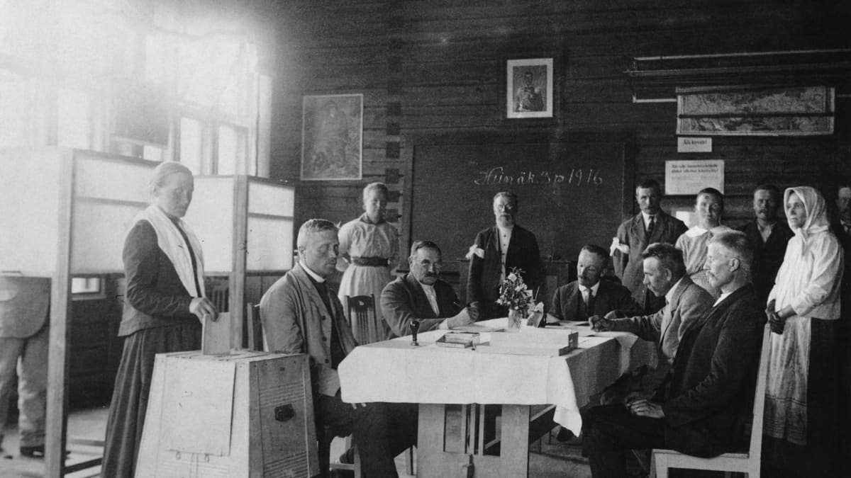 Vaalitoimitsijoita. Äänestäjä pudottaa äänestyslippuaan vaaliuurnaan Hauhon koululla eduskuntavaaleissa 1916.