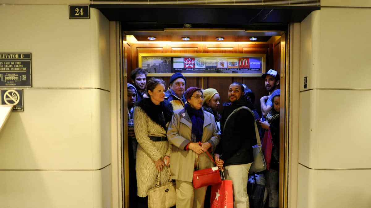 Paljon ihmisiä hississä.