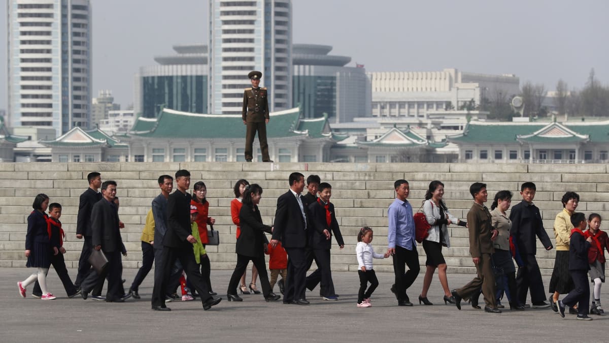 Pohjoiskorealainen sotilas katselee ihmisiä, jotka kävelevät maan perustajan syntymäpäivän vuosipäivää juhlistavaan kukkanäyttelyyn.