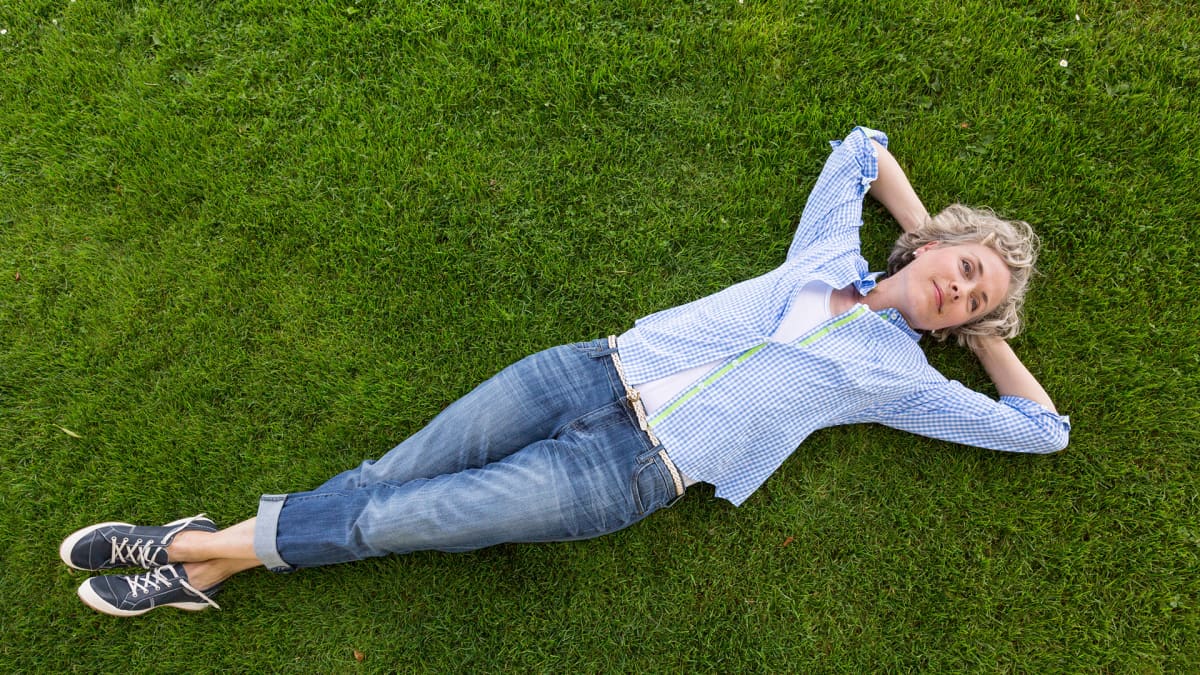 Nainen makaa nurmikolla