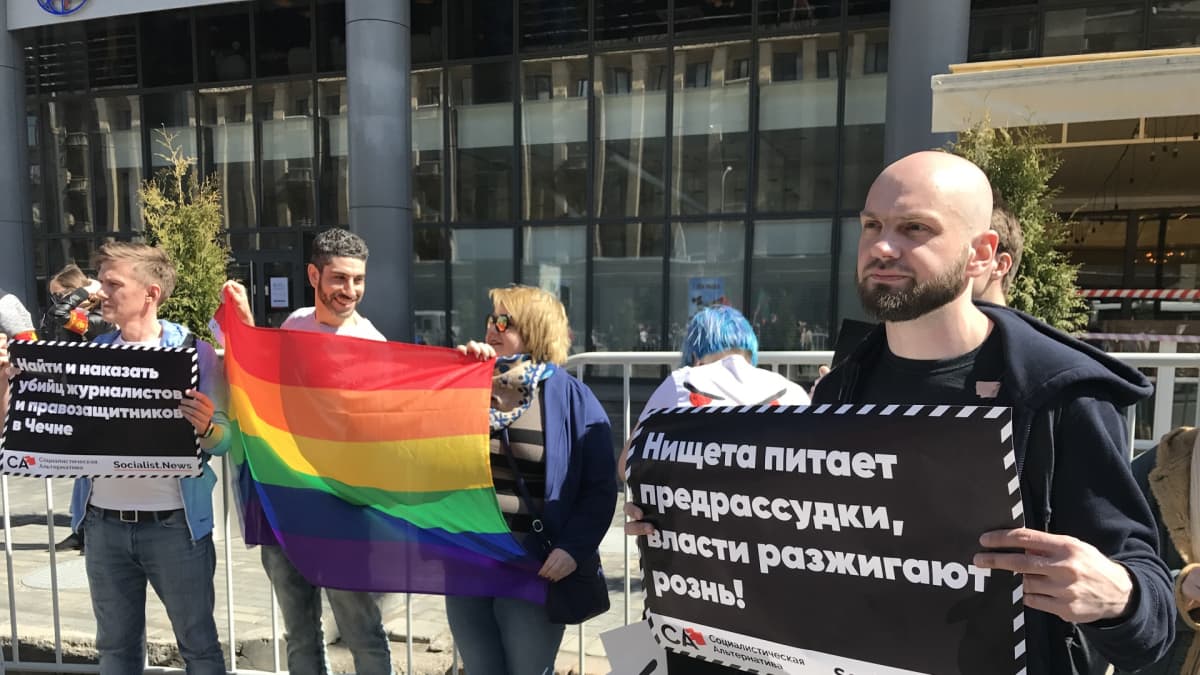 Ilja Jašin ja muutama mielenosoittaja, joilla sateenkaarilippu.