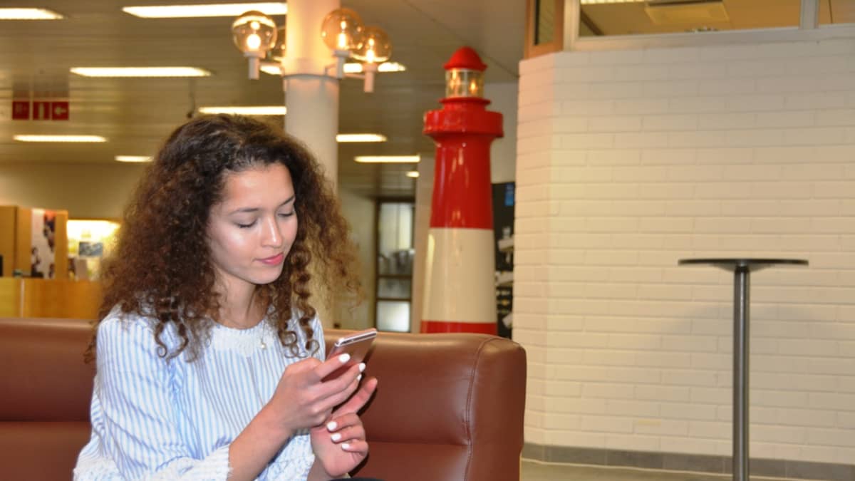 Amanda Rahmani istuu kaupungintalon aulassa kännykkä kädessään.