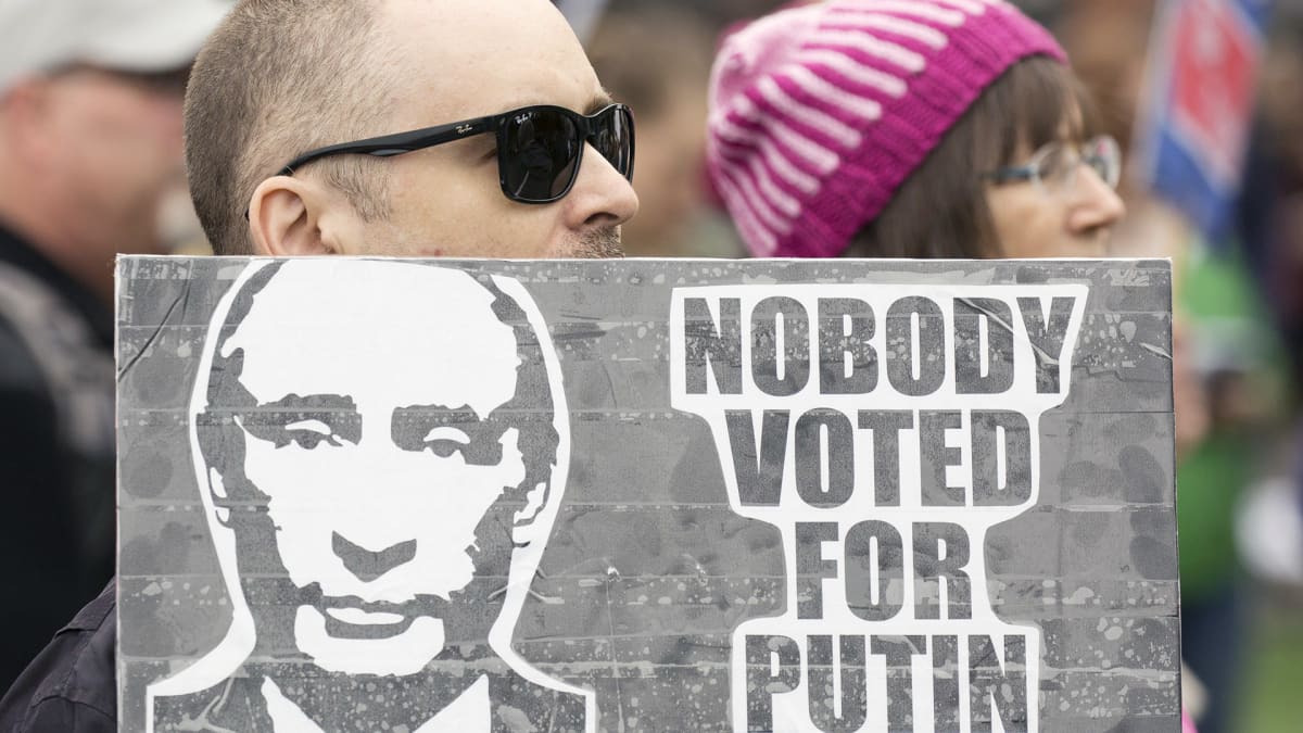 Mies kantaa Putinin vastaista kylttiä Trumpia vastaan osoitetussa mielenosoituksessa Washingtonissa .