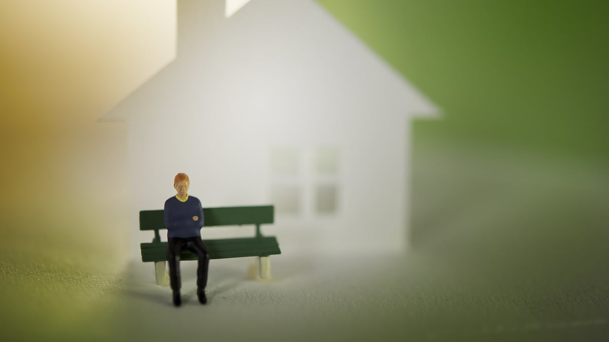 Miniatyyrimies istuu yksin talon edessä.