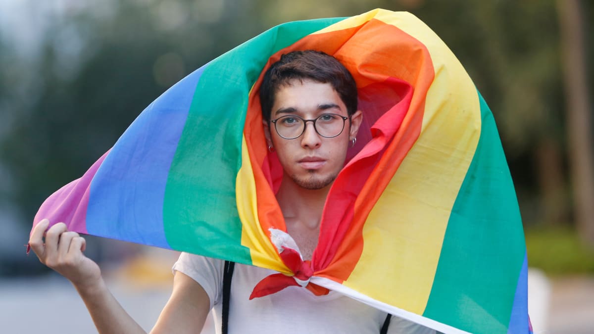 Pride-marssille osallistunut henkilö sateenkaarilipun alla.