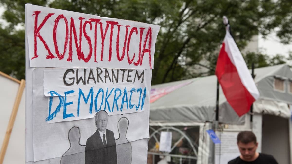 Mielenosoittajien kyltti, jossa teksti: konstytucja gwarantem demokracji.