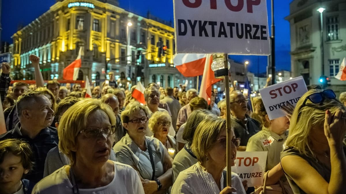 Hallituksen vastaiset mielenosoittajat kantavat käsissään kylttejä Puolassa.