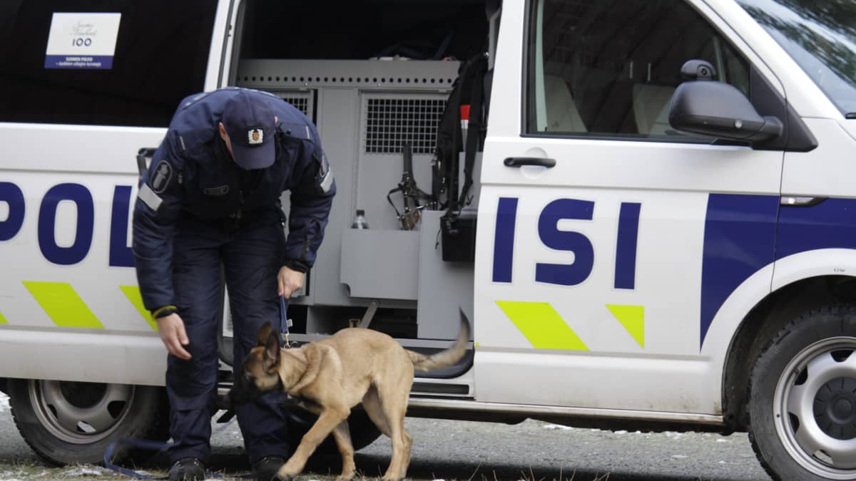 Poliisi ja koira poliisin partioauton edessä