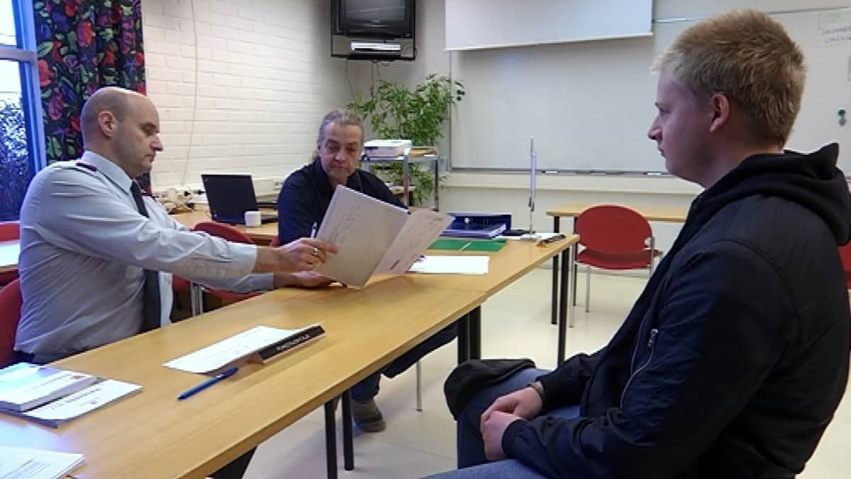 Nuori mires istuu tuolilla ja viranomaiset pöydän takana selaavat papereita