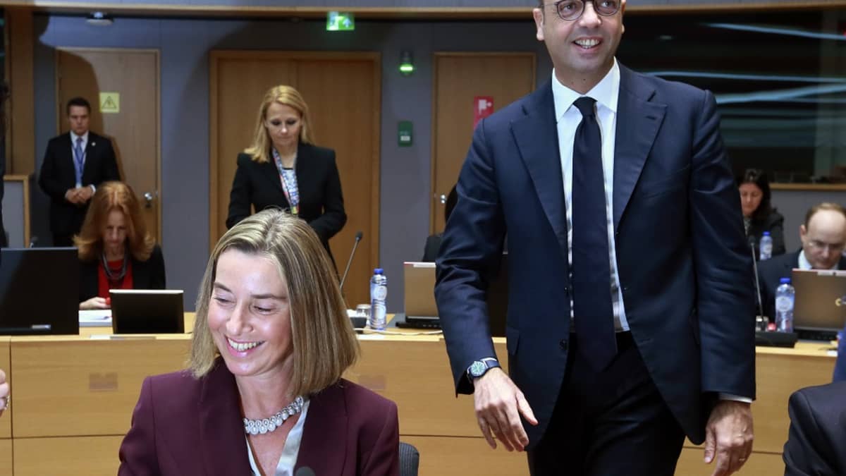 Mogherini istuu hymyillen etualalla vasemmalla. 