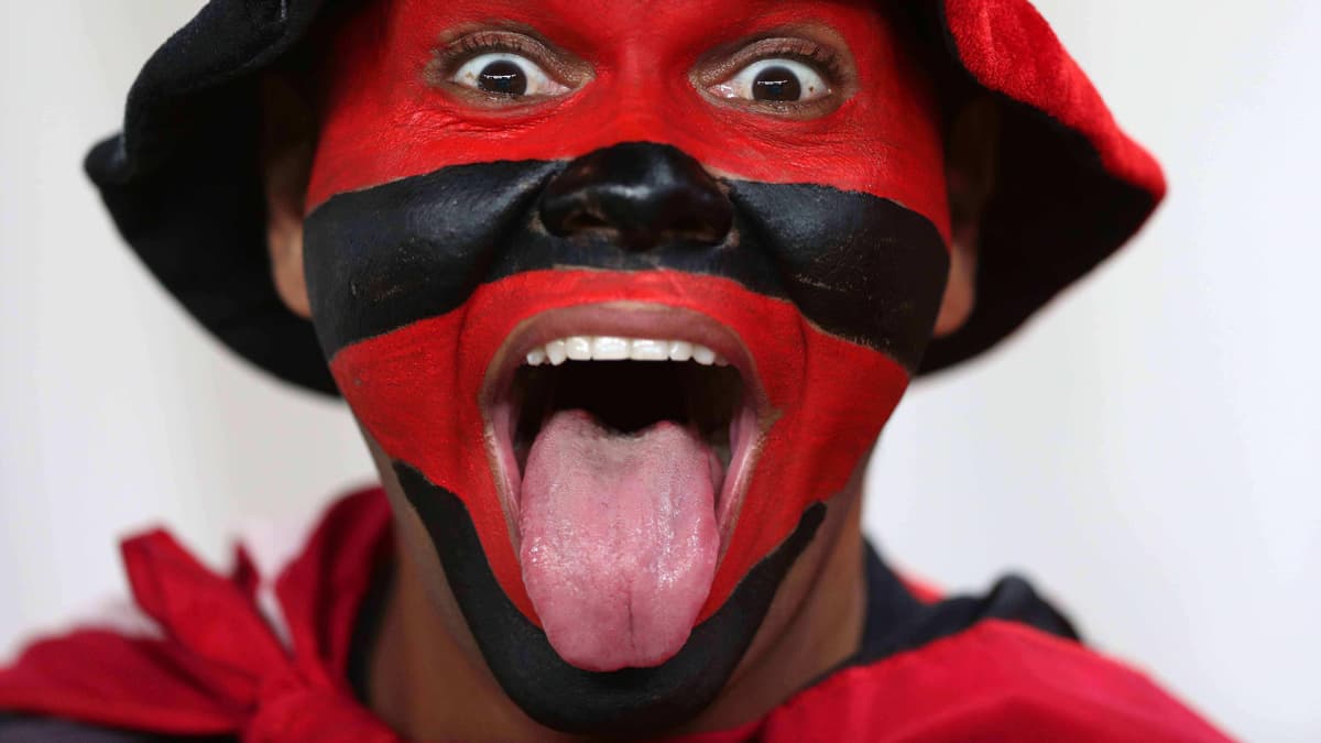 Poika jolla kasvot maalattu punaisin ja mustin raidoin näyttää kieltä