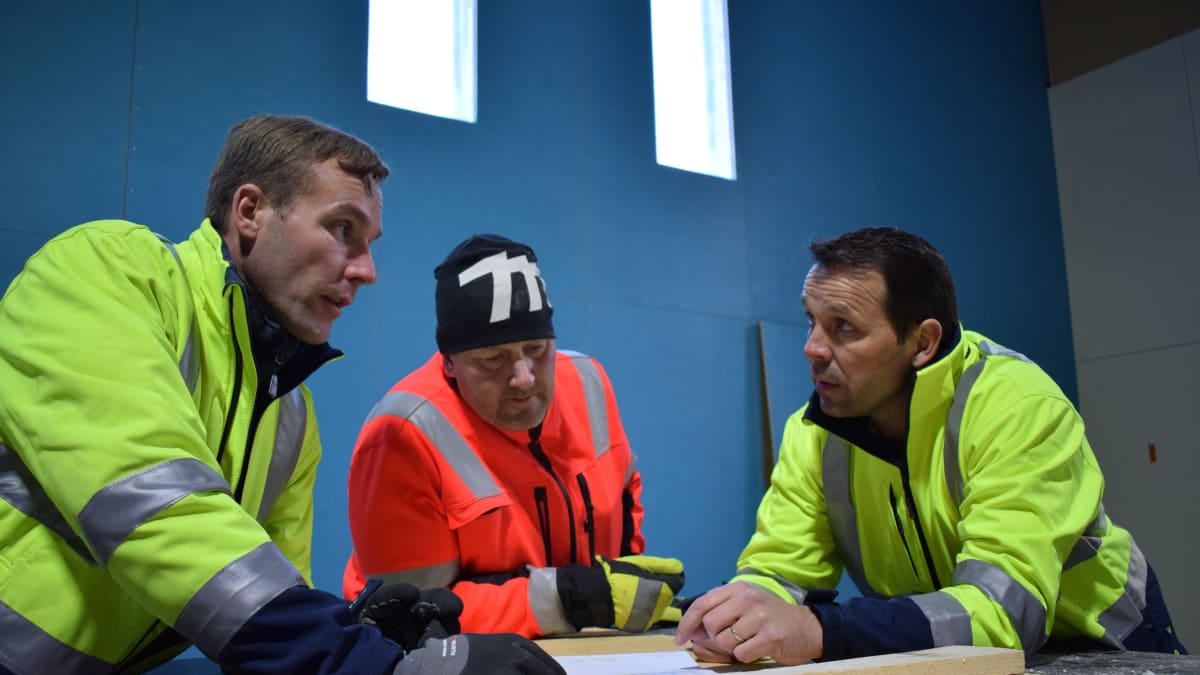 Vesa Rantanen, Ville Arkkila ja Paavo Kallio pitävät palaveria monitoimihallin rakennustyömaalla.