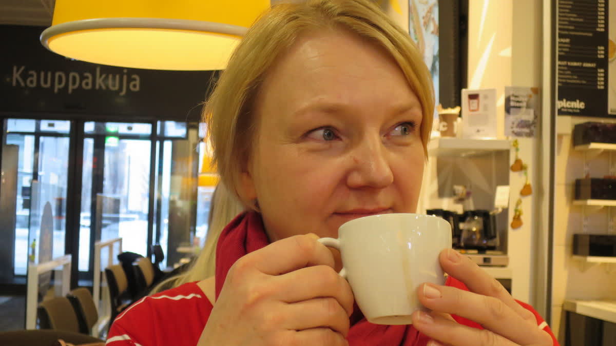 Vaalea nainen juomassa kahvia kahvilassa