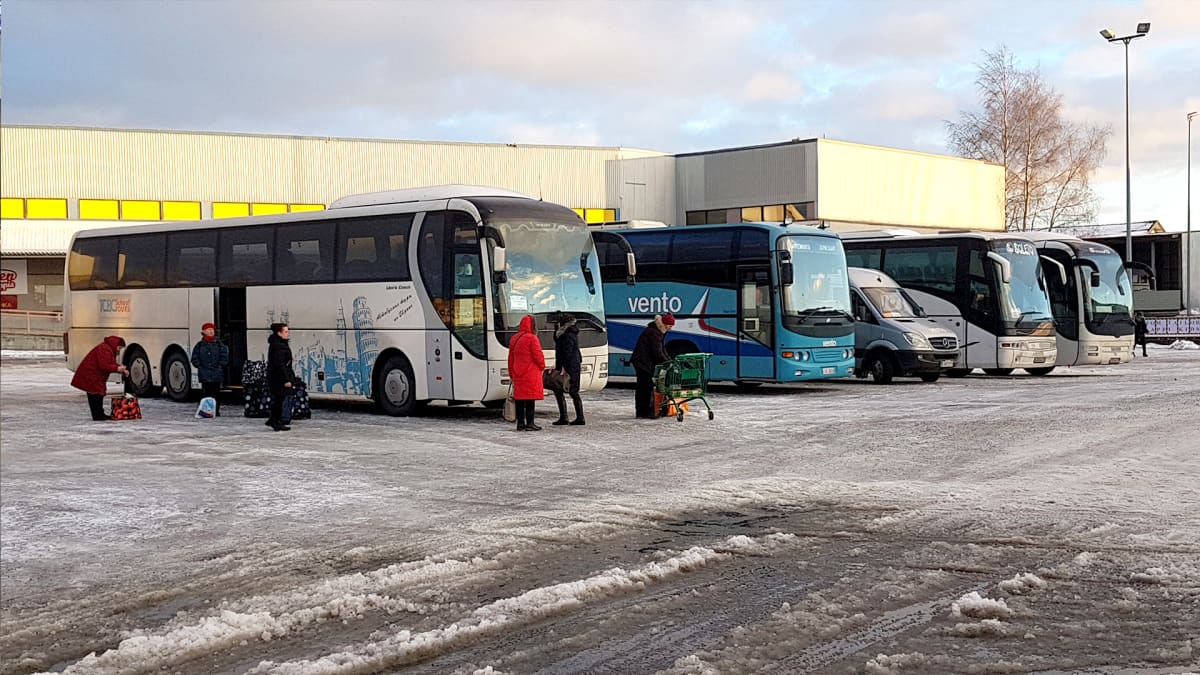 Venäläisiä busseja Prisman parkkipaikalla. Venäläisiä turisteja ostoskasseineen ulkopuolella.