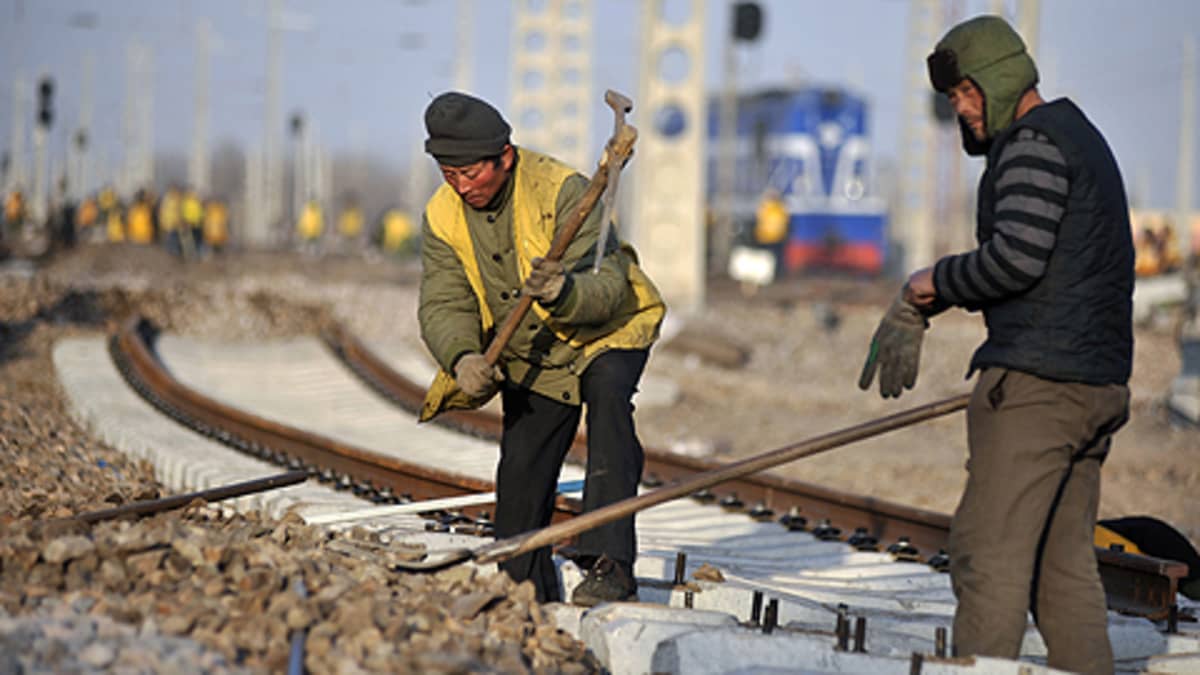 Kaksi siirtolaista kiinnittää rautatien kiskoja Shandongin maakunnassa joulukuussa vuonna 2009.