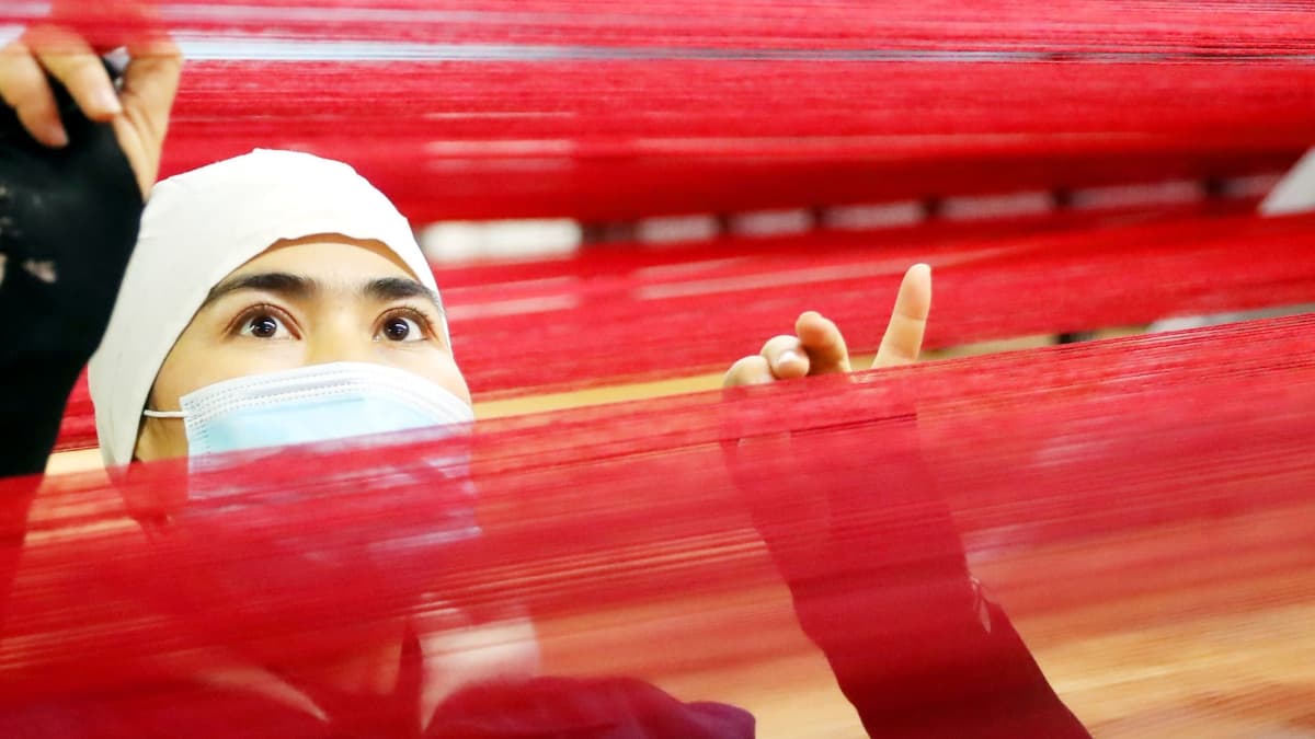 Mattoja valmistavan tuontantolaitoksen työntekijä Ürümqin kaupungissa Xinjiangissa marraskuussa 2020.