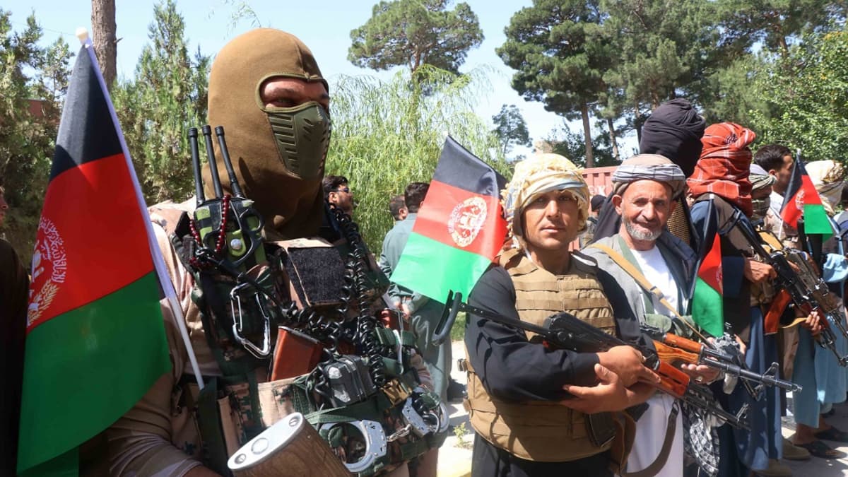 Kuvassa etualalla kasvonsa naamioilla peittänyt sotilas. Hänen vieressään seisoo kaksi aseistautunutta siviilimiestä. 