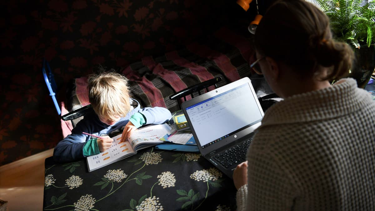  Koulusta kotiin jäänyt lapsi opiskelee yhdessä etätöitä tekevän äidin kanssa kotonaan.