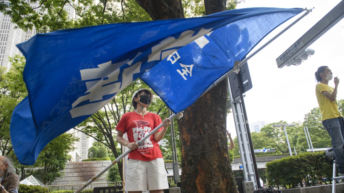 Opiskelija Hiro Yajima heilutti mielenosoituksessa lippua.
